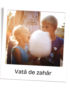Two children share a large white cotton candy outdoors, girl about to bite while boy watches.